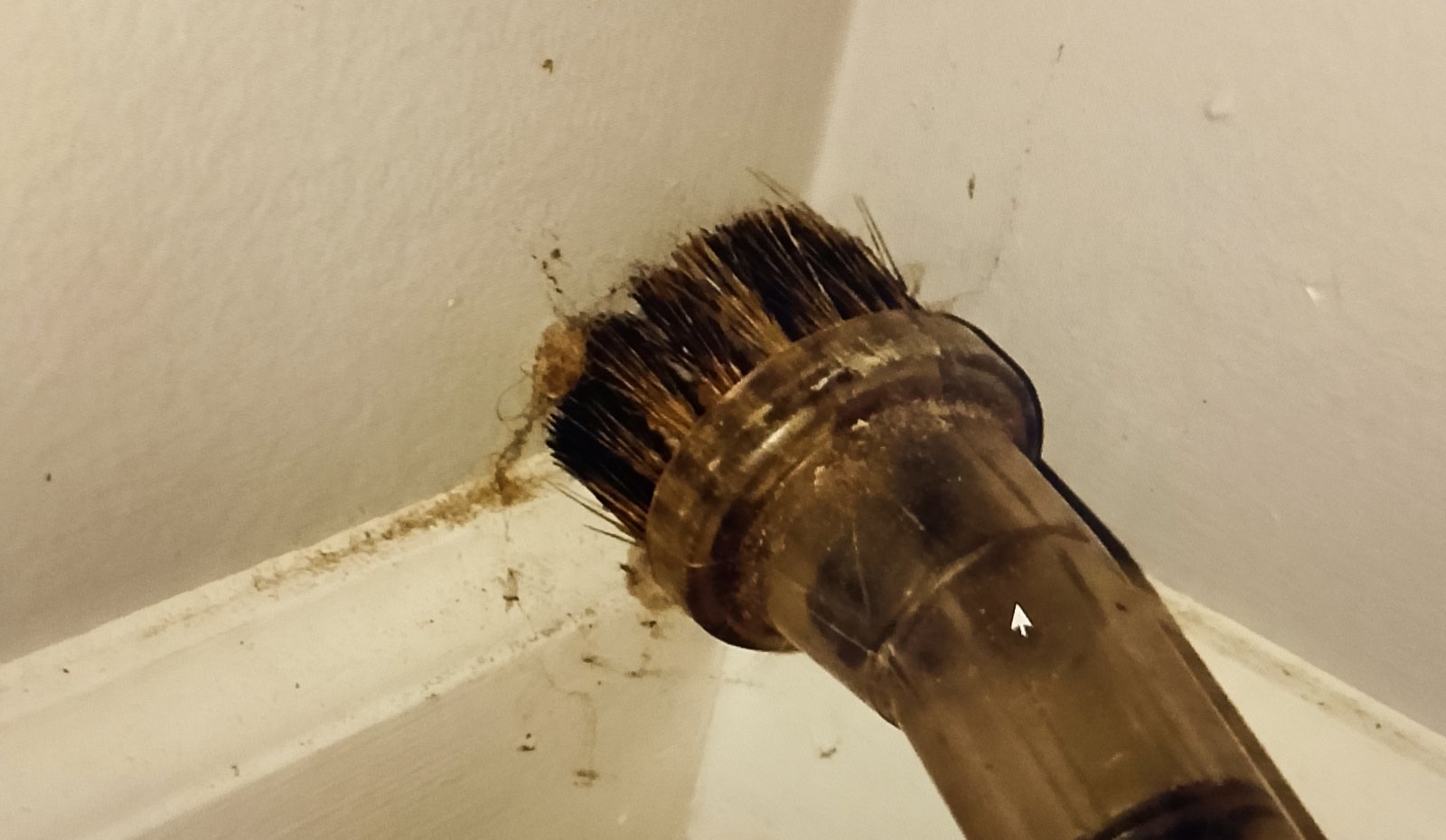 A close up of a vacuum A close-up of a vacuum brush attachment gently running along a baseboard or wall corner.