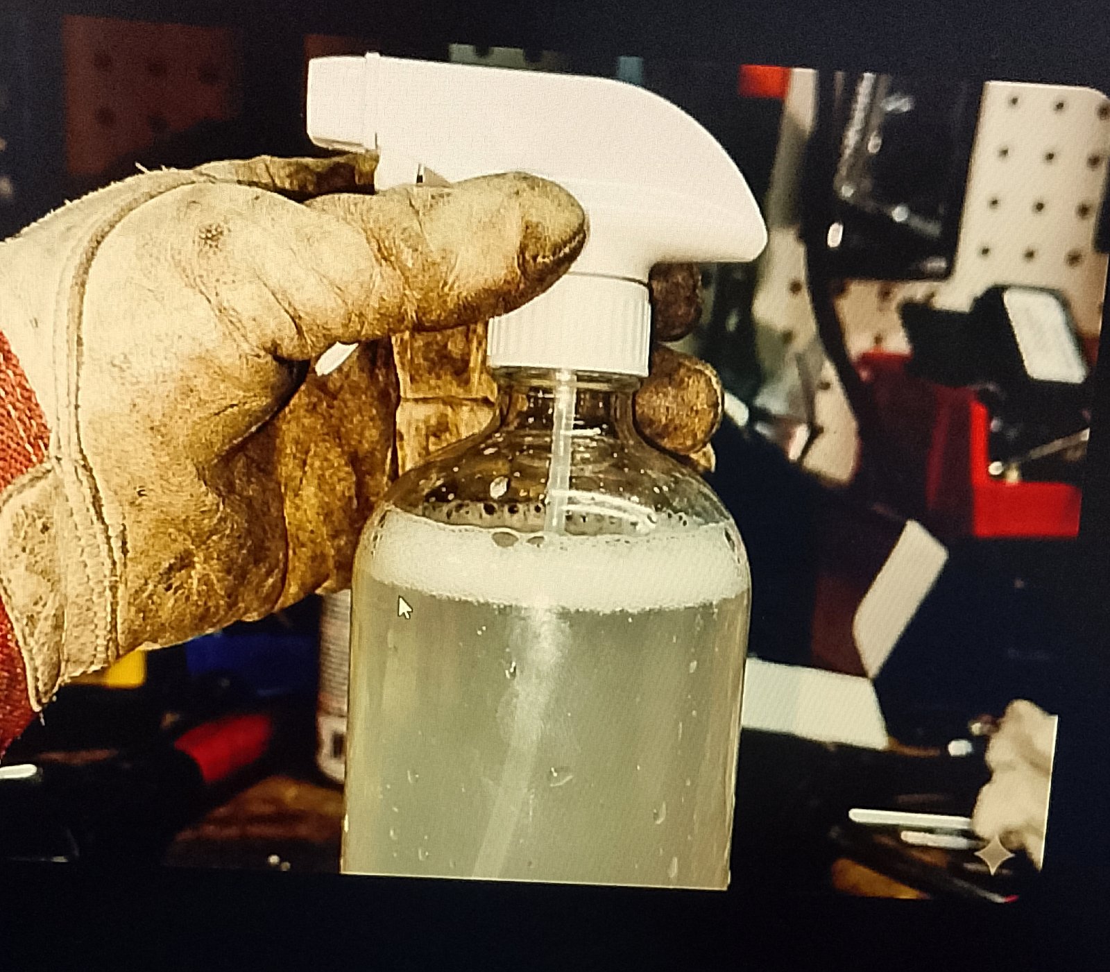 Close-up of the spray bottle nozzle being screwed on, with the liquid inside showing a slight separation of bubbles at the top.