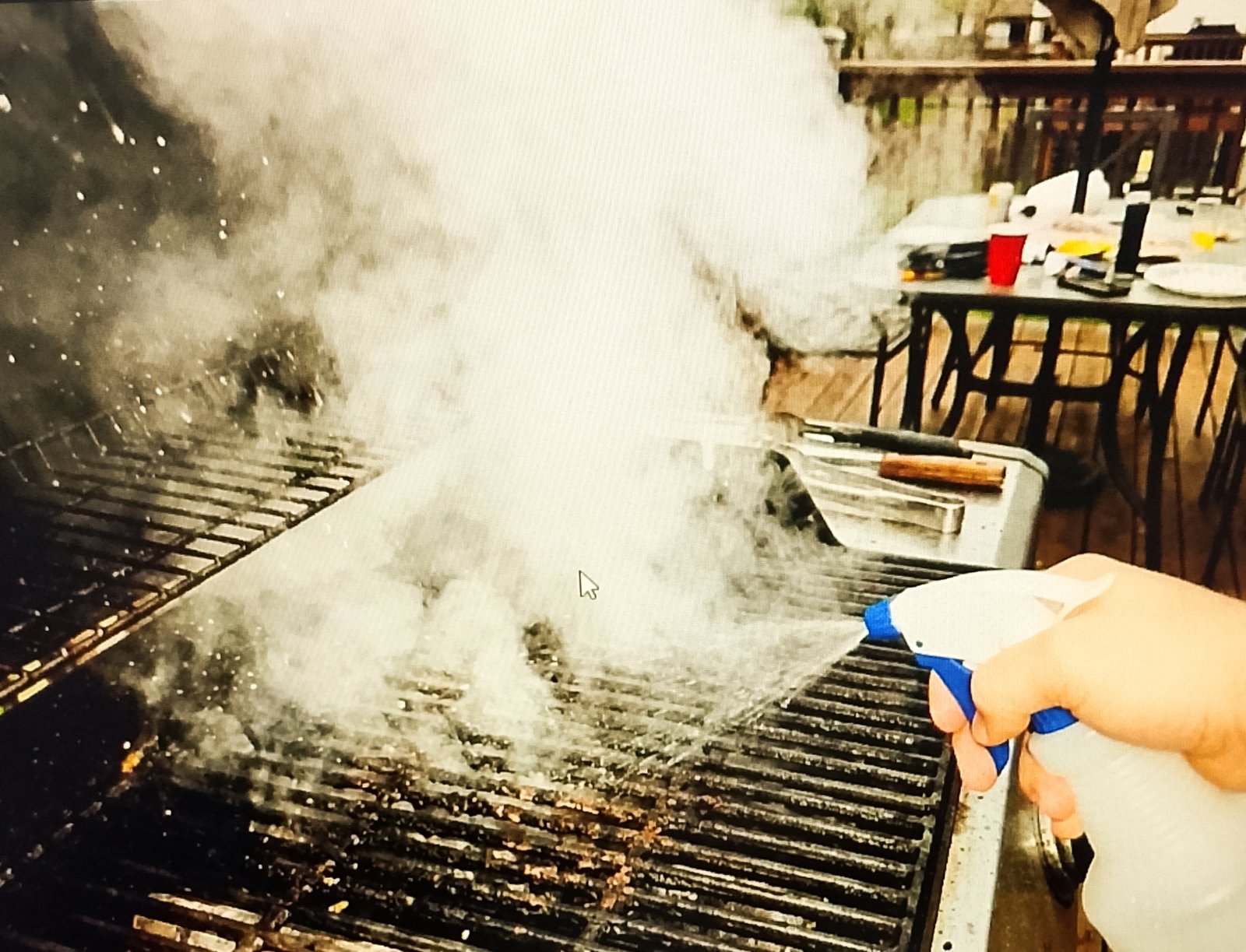 Spraying water on hot grill grates to create steam