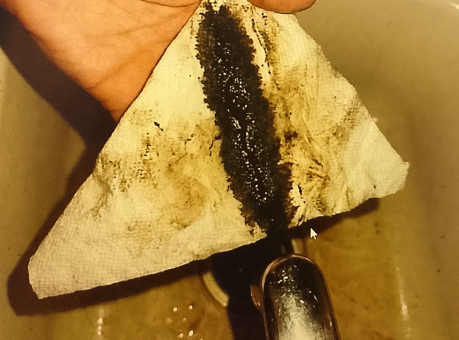 Cleaning the grease channel of a George Foreman grill with folded paper towel