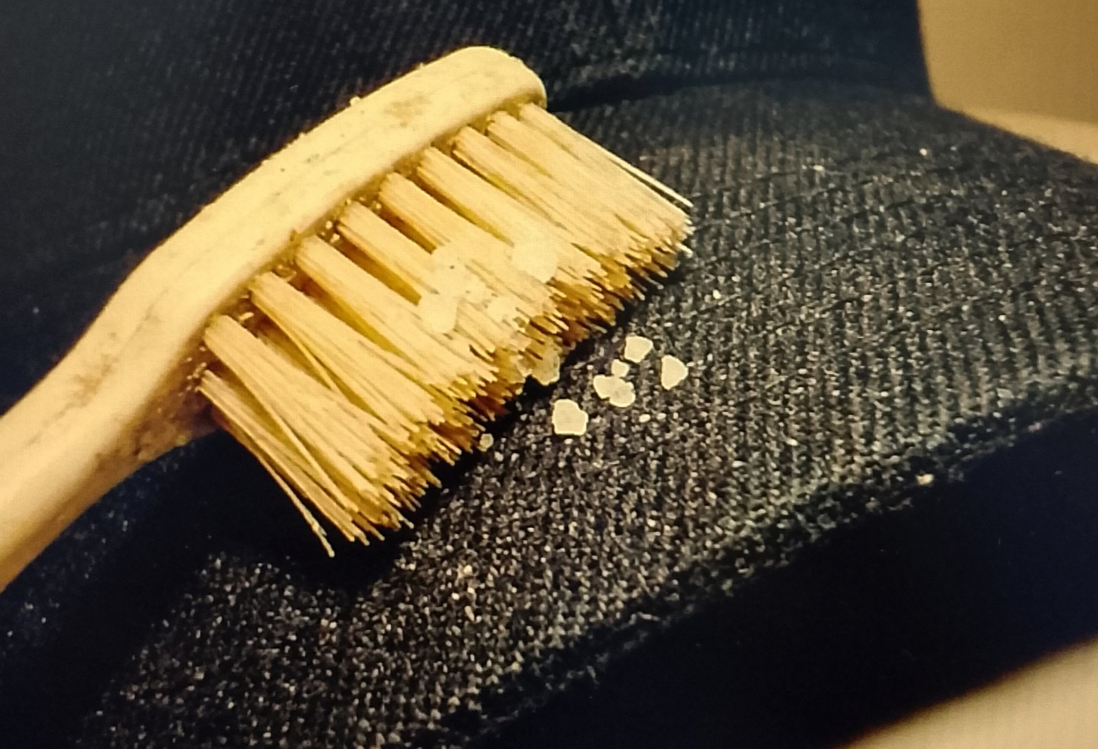 tothbrush lifting white salt Soft toothbrush lifting white salt crystals from a dark fabric brim