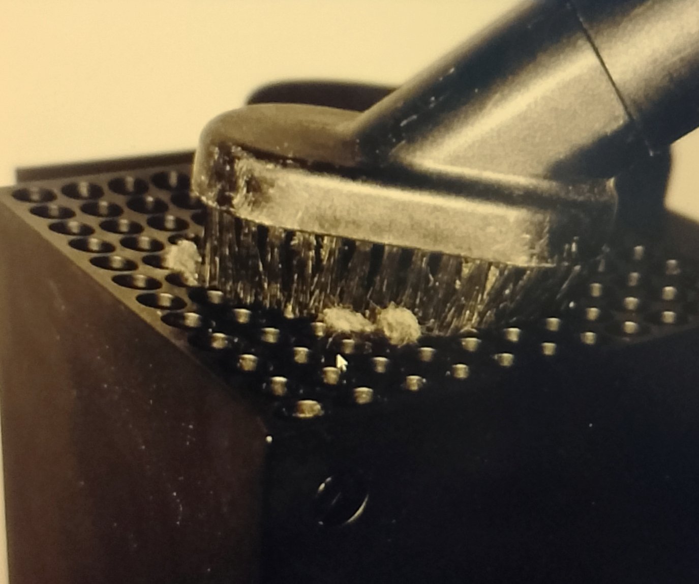 Vacuum brush head gently touching the top circular grate of the Xbox Series X
