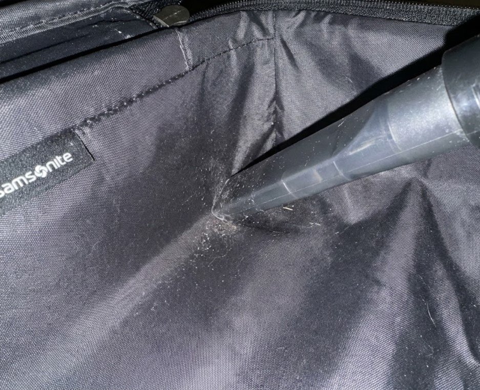 Vacuuming the interior seams of a Samsonite suitcase