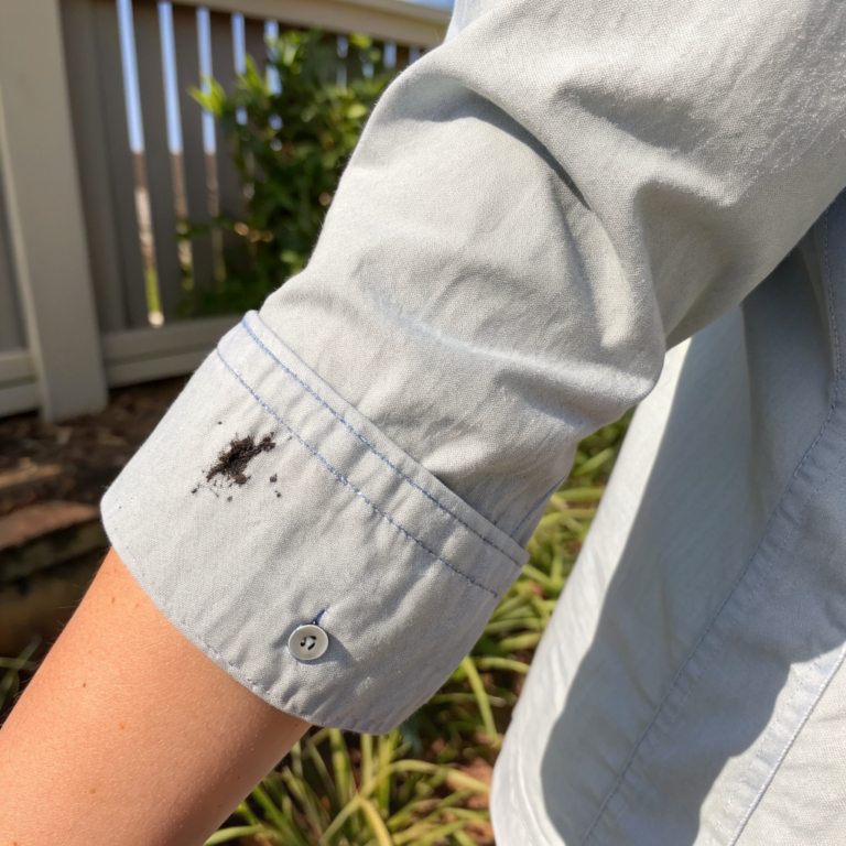 Black mascara smear staining the cuff of a light gray shirt