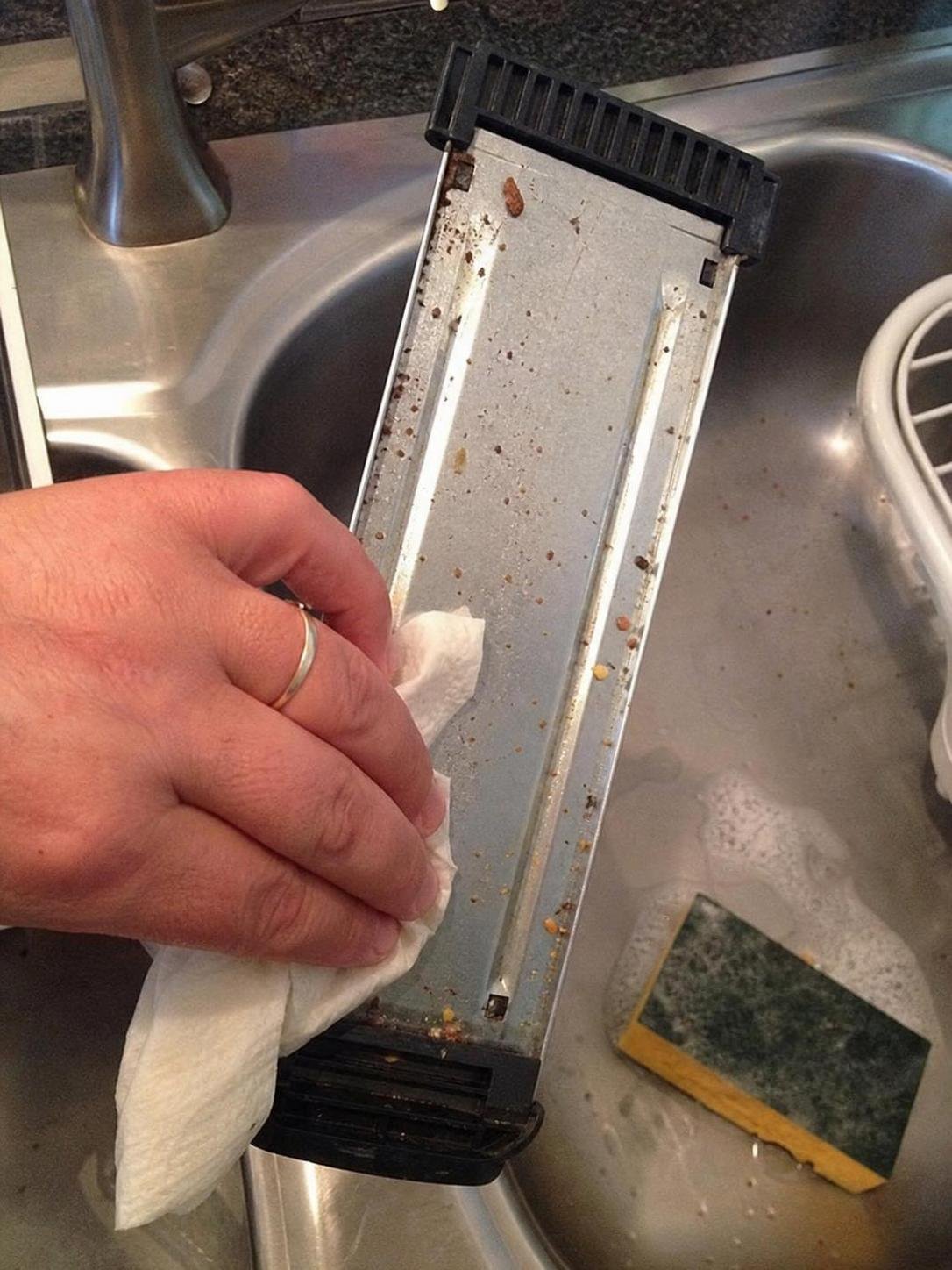 Close-up household cleaning method for how to clean a toaster crumb tray; best way to clean a toaster crumb tray; clean a toaster crumb tray without damage; safe cleaner for a toaster crumb tray; a toaster crumb tray cleaning mistakes; how often to clean a toaster crumb tray